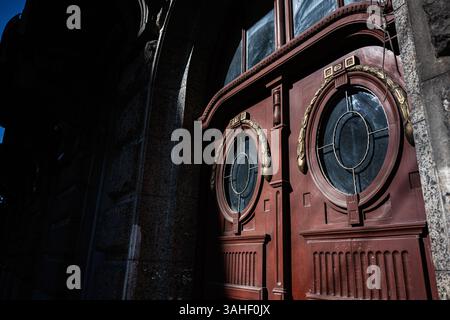 Portes doubles peintes avec fenêtres circulaires et détails dorés décoratifs sous lumière naturelle Banque D'Images