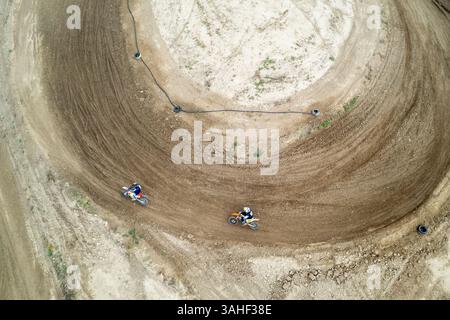 Vue aérienne de deux motocross conduisant leurs vélos sur une piste en terre battue pendant une course Banque D'Images