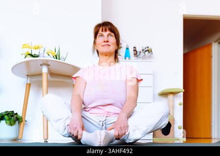 femme d'âge moyen en surpoids faisant du yoga à la maison Banque D'Images