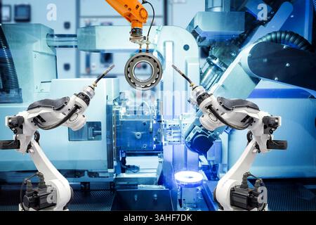 Robot industriel de soudage et robot de préhension travaillant avec des pièces métalliques sur usine intelligente, sur fond de couleur bleu machine, industrie 4,0 Banque D'Images