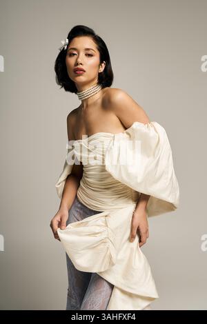 Une belle jeune mariée met en valeur sa robe élégante et sa présence confiante dans un cadre serein. Banque D'Images
