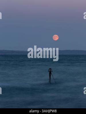 Super Moon se levant au-dessus des falaises de Whitsand Bay Cornwall pris de Looe, y compris Little mine à l'entrée de Looe Harbour Banque D'Images