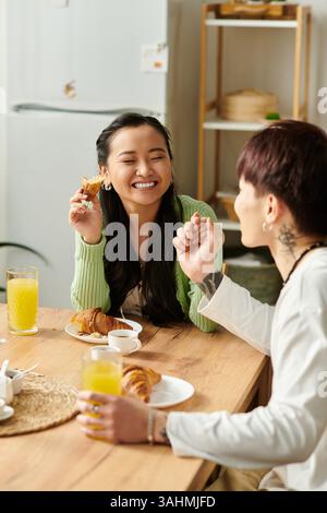 Un jeune couple profite d'un délicieux petit déjeuner ensemble à la maison, souriant et partageant la nourriture. Banque D'Images