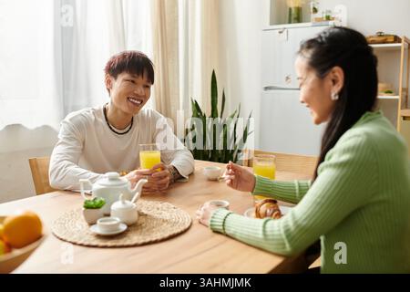 Un jeune couple profite du petit déjeuner ensemble à la maison, souriant et partageant une conversation délicieuse. Banque D'Images