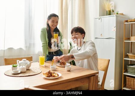 Un jeune couple profite d'un délicieux petit déjeuner à la maison, partageant sourires et nourriture ensemble. Banque D'Images