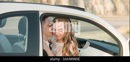 Couple de bannière partage moment tendre dans la voiture garée pendant le coucher du soleil, copie de l'espace. Amour, connexion, intimité et joie paisible capturés dans un romantique franc Banque D'Images