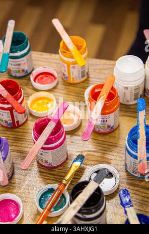 Une table avec de nombreuses bouteilles de peinture et pinceaux de couleurs différentes Banque D'Images