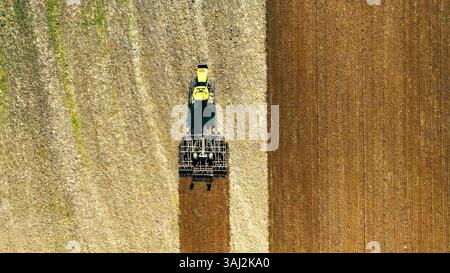 Vue de dessus d'un tracteur labourant un grand champ. Vue de haut en bas d'un tracteur labourant un grand champ sec. Banque D'Images