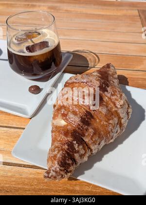 Croissant et café glacé sur table en bois Banque D'Images