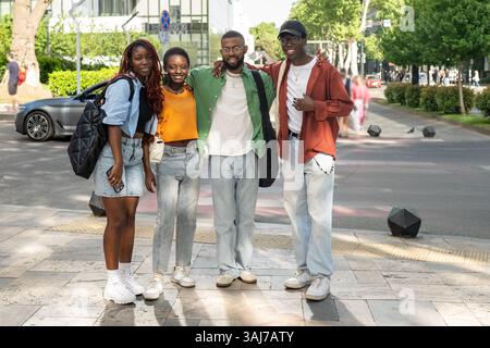 Heureux jeune groupe multiculturel d'amis se tiennent ensemble, embrassant et souriant à la caméra sur la marche Banque D'Images