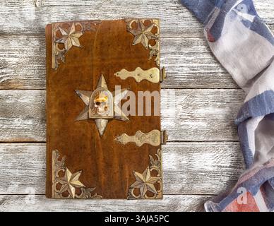 Un vieux livre avec couverture décorative sur une vieille table de planches Banque D'Images