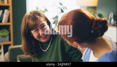 Personnes âgées, femme et soignant avec parler ou rire sur le canapé dans la maison de retraite pour le soutien, l'histoire drôle et la gentillesse. Personne senior, infirmière et Happy In Banque D'Images
