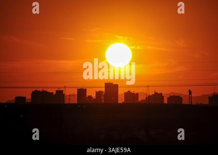 Phoenix, Arizona, États-Unis. 10 avril 2025. Le soleil plane au-dessus des gratte-ciel du centre-ville de Phoenix au coucher du soleil, vu depuis le lac de Tempe Town alors que la chaleur de la journée commence à s'apaiser. Jeudi a marqué le premier jour à trois chiffres de 2025 dans la région de Phoenix, arrivant près d'un mois plus tôt que d'habitude et suivant un record de 2024 avec 70 jours à ou au-dessus de 110 degrés. (Crédit image : © Eduardo Barraza/ZUMA Press Wire) USAGE ÉDITORIAL SEULEMENT ! Non destiné à UN USAGE commercial ! Banque D'Images