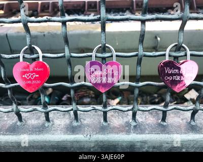 Cologne, Allemagne - 18 mars 2022 trois serrures en forme de cœur sont accrochées à une clôture. Les serrures sont roses et portent les noms du couple qui s'est marié Banque D'Images