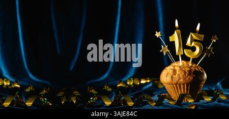 Fête de l'âge à venir 15ème anniversaire. cupcake au chocolat avec la bougie numéro quinze sur fond bleu velours. Bannière Banque D'Images