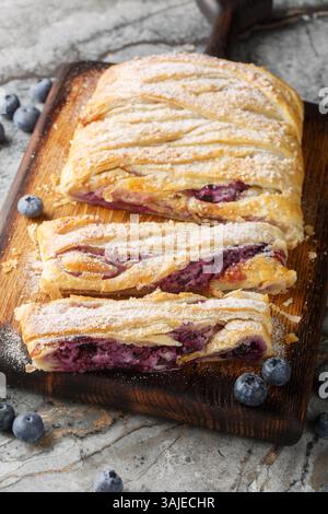 Pâte feuilletée aux myrtilles avec un remplissage de fromage à la crème gros plan sur une planche de bois sur la table. Vertical Banque D'Images