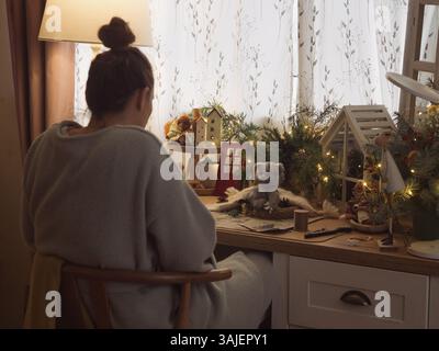 Vue arrière d'une femme fabriquant à un bureau avec des décorations de Noël Banque D'Images