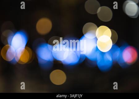 Lumières nocturnes urbaines défocalisées avec cercles bokeh bleus et dorés Banque D'Images