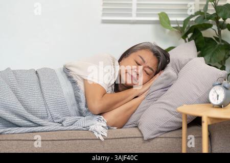 Repos et bien-être. Une femme âgée dormant paisiblement sur un canapé, embrassant la tranquillité et la santé. Banque D'Images