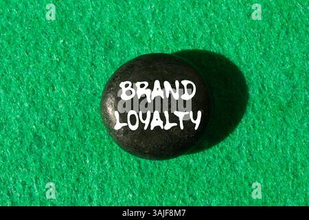 Message de fidélité à la marque écrit sur pierre noire sur fond vert. Symbole conceptuel de fidélité à la marque. Copier l'espace. Banque D'Images