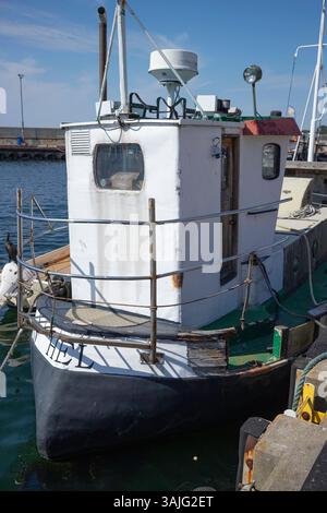 Un petit bateau avec les lettres 'HE' sur le côté. Le bateau est amarré à un quai Banque D'Images