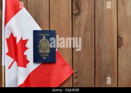 Concept de citoyenneté canadienne, drapeau de feuille d'érable rouge avec passeport sur fond de bois avec espace de copie Banque D'Images