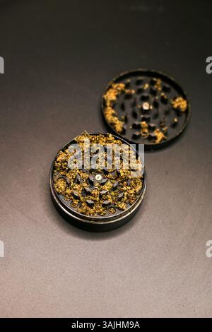 Gros plan d'un moulin rempli de cannabis écrasé sur une surface noire. Banque D'Images