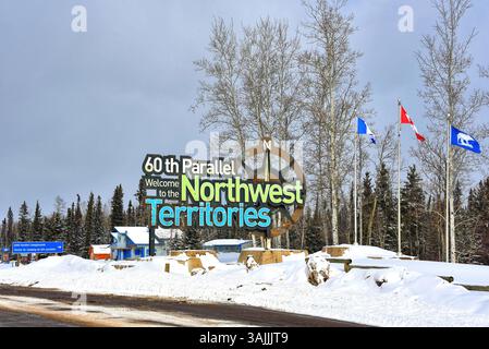 Territoires du Nord-Ouest, Canada - 1er avril 2025 : Bienvenue dans les Territoires du Nord-Ouest signe à la frontière de l'Alberta avec les drapeaux du Canada et un drapeau avec un BE polaire Banque D'Images