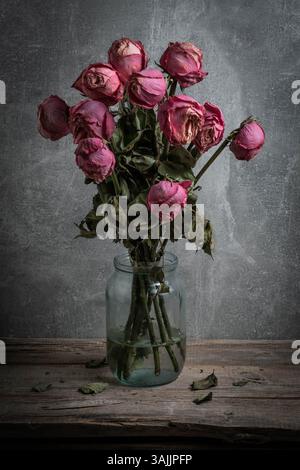 Bouquet de roses séchées dans un bocal en verre sur une table en bois Banque D'Images