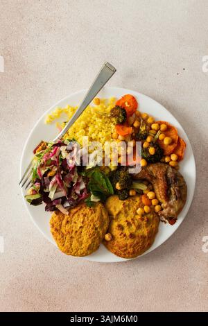 Un petit déjeuner sain avec des crêpes lentilles-courgettes, du millet, du cou de poulet rôti, des patates douces, du brocoli, carottes, pois chiches et salade fraîche mélangée avec des radis, des noix et des germes de haricots mungo Banque D'Images