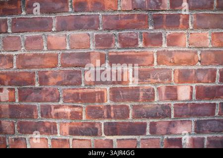 Vue détaillée du mur de briques montrant les fissures, l'érosion, les marques de vieillesse et la texture industrielle souvent utilisée comme fond grunge ou élément de design urbain Banque D'Images