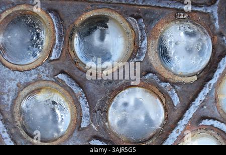 Feuille de métal rouillée grungy avec des trous de verre circulaires et une surface sale. Texture industrielle avec corrosion, taches de rouille, acier vieilli et verre brisé. Nous Banque D'Images