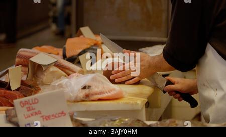 Poissonnier préparant un steak de thon, tranchant du poisson frais sur une planche à découper à l'étal du marché des fruits de mer Banque D'Images