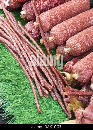Sélection savoureuse de saucisses artisanales et d'en-cas présentés sur un étal de marché animé pendant une journée ensoleillée Banque D'Images