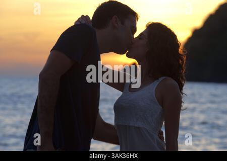8 mai 2014 - Thaïlande - couple amoureux s'embrassant au coucher du soleil sur la plage. Baie de Kantiang. Koh Lanta. Thaïlande. Asie. La baie de Kantiang est surtout connue comme l'emplacement de Pimalai, le premier hôtel de luxe de Koh Lantaâ€ ™. Il y a maintenant plusieurs autres hôtels, resorts et villas sur la baie de Kantiang que nous recommandons. Cliquez sur n'importe quel lien pour voir plus de photos, lire les commentaires des clients et réserver en ligne. La baie de Kantiang crée une forme de croissant parfaite pour garder la mer d'Andaman calme et calme avec une eau cristalline. En regardant vers le haut de la plage au-delà de la route, vous verrez la chaîne de montagnes qui offre des paysages à couper le souffle autour de la baie. Banque D'Images