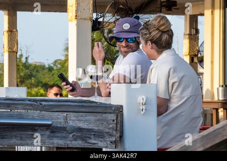 Couple souriant profitant d'un verre de vin ensemble au coucher du soleil dans un café en bord de mer sur l'île d'Amelia à Fernandina Beach, en Floride. (ÉTATS-UNIS) Banque D'Images