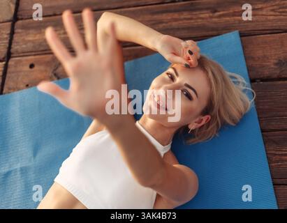 Femme de fitness joyeuse se trouve sur un tapis en plein air. Concept de mode de vie sain Banque D'Images