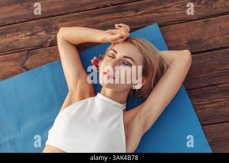 Femme de fitness de beauté se trouve sur un tapis en plein air. Concept de mode de vie sain Banque D'Images