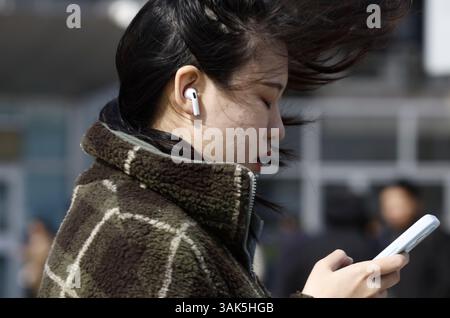 Pékin, Chine. 12 avril 2025. Une femme marche sur la place sud de la gare de Pékin Ouest à Pékin, capitale de la Chine, le 12 avril 2025. De nombreuses régions du nord de la Chine subissent des vents de force de vent et des baisses de température samedi. Crédit : Zhang Yuwei/Xinhua/Alamy Live News Banque D'Images