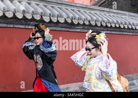 Pékin, Chine. 12 avril 2025. Des gens marchent dans une rue à Pékin, capitale de la Chine, le 12 avril 2025. De nombreuses régions du nord de la Chine subissent des vents de force de vent et des baisses de température samedi. Crédit : Jiang Han/Xinhua/Alamy Live News Banque D'Images