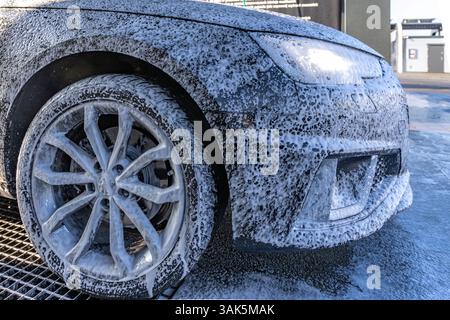 Mousse pénétrante active blanche sur la carrosserie, lavage de voiture dans un lave-auto sans contact, produits chimiques pour voiture Banque D'Images