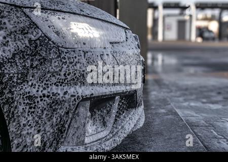 Mousse pénétrante active blanche sur la carrosserie, lavage de voiture dans un lave-auto sans contact, produits chimiques pour voiture Banque D'Images