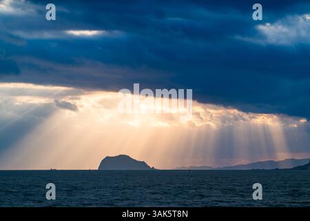 Les rayons de soleil dorés traversent les nuages sombres, projetant une lueur à couper le souffle sur une île solitaire de Keelung dans le vaste océan. Jinshan, New Taipei ci Banque D'Images