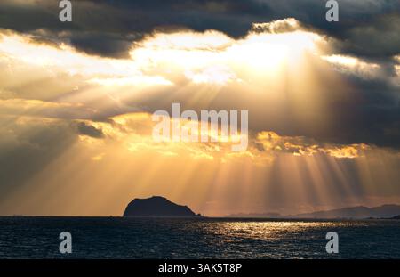 Les rayons de soleil dorés traversent les nuages sombres, projetant une lueur à couper le souffle sur une île solitaire de Keelung dans le vaste océan. Jinshan, New Taipei ci Banque D'Images