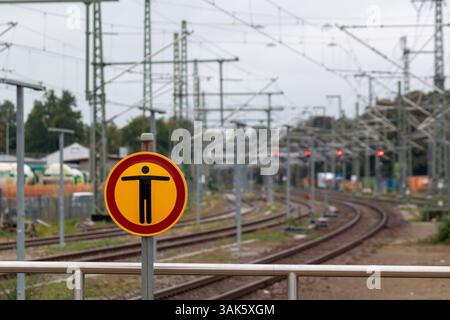 Le panneau est monté sur un poteau métallique au premier plan, avec des voies ferrées courbées dans la distance derrière elle Banque D'Images