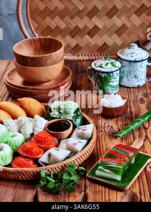 Des gâteaux indonésiens traditionnels colorés, également connus sous le nom de 'Kue basah', sont exposés sur une poêle en bambou tissé avec une couche de feuilles de bananier. Idéal pour culinaire Banque D'Images