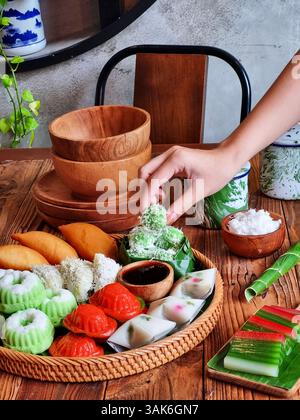 Des gâteaux indonésiens traditionnels colorés, également connus sous le nom de 'Kue basah', sont exposés sur une poêle en bambou tissé avec une couche de feuilles de bananier. Idéal pour culinaire Banque D'Images