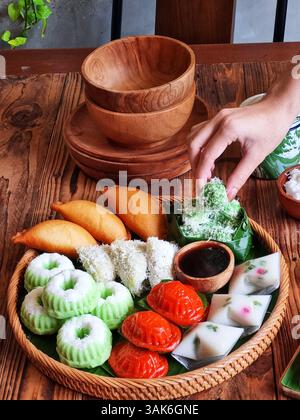 Des gâteaux indonésiens traditionnels colorés, également connus sous le nom de 'Kue basah', sont exposés sur une poêle en bambou tissé avec une couche de feuilles de bananier. Idéal pour culinaire Banque D'Images
