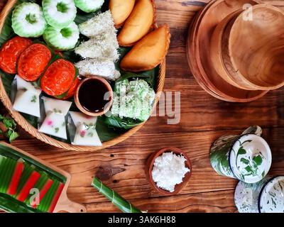 Des gâteaux indonésiens traditionnels colorés, également connus sous le nom de 'Kue basah', sont exposés sur une poêle en bambou tissé avec une couche de feuilles de bananier. Idéal pour culinaire Banque D'Images