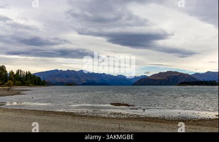 Lac Wanaka, un après-midi nuageux d'été avec une chaîne de montagnes et la ville de Wanaka sur le rivage. Île du Sud, Nouvelle-Zélande Banque D'Images